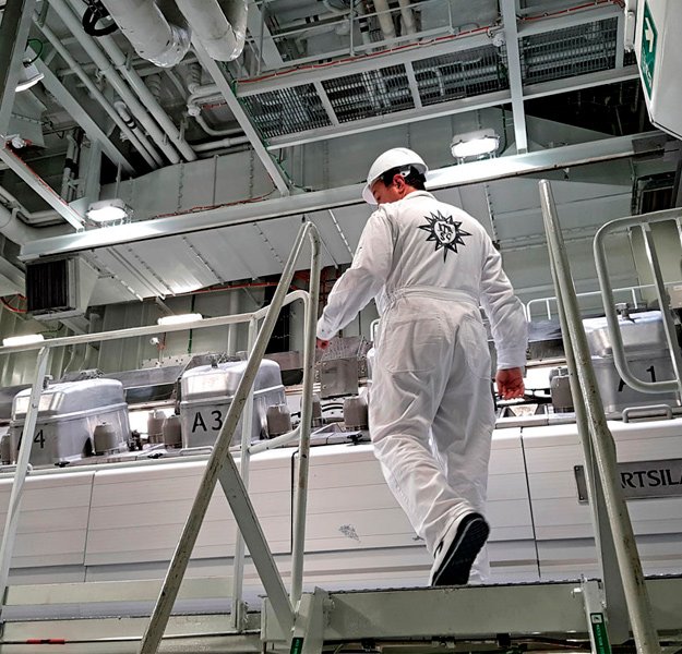 An engineer in uniform walking up steps in the engine room of a cruise ship | MSC Cruises An engineer in uniform walking up steps in the engine room of a cruise ship | MSC Cruises