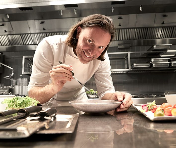 A chef plating a gourmet dish in a modern kitchen | MSC Cruises